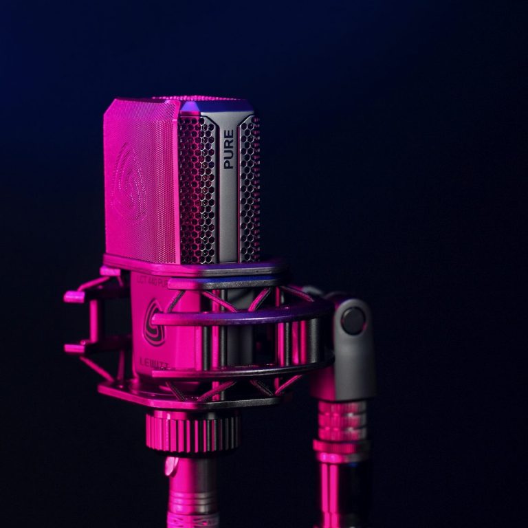 <img source='pic.gif' alt='Vibrant microphone on a stand with pink and blue lighting against a dark background.' />.