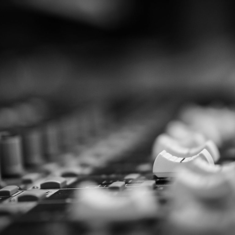 <img source='pic.gif' alt='Black and white close up of mixing board and knobs in recording studio.' />.